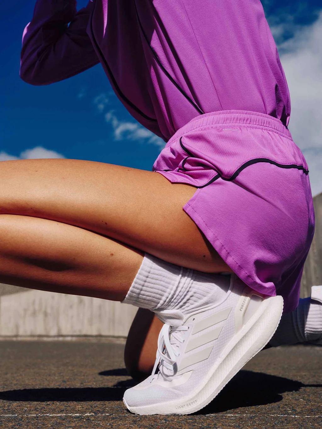 Woman wearing pink adidas sportswear with white adidas Pureboost 5 trainers