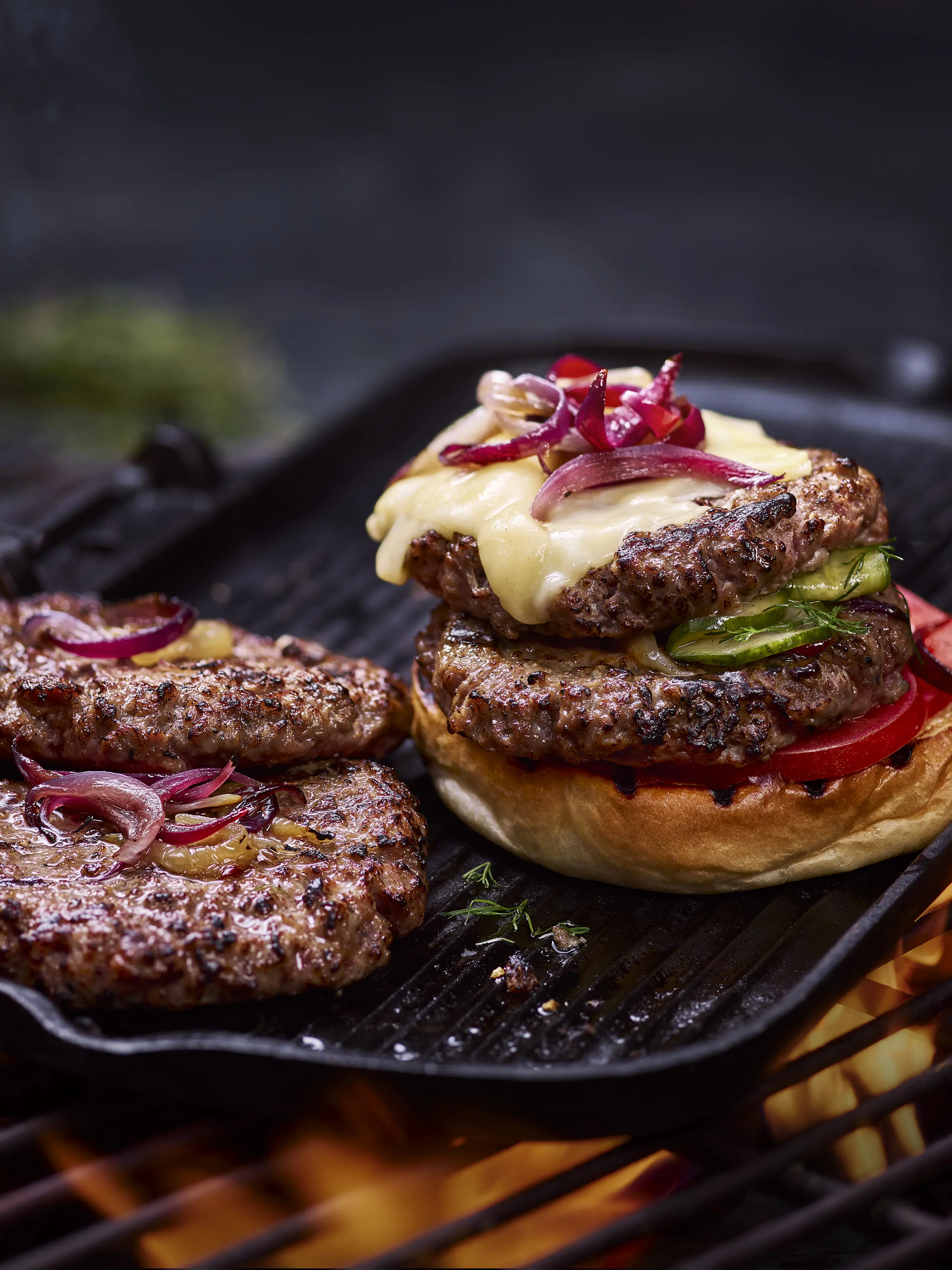 Smashed burgers on the grill with melted cheese