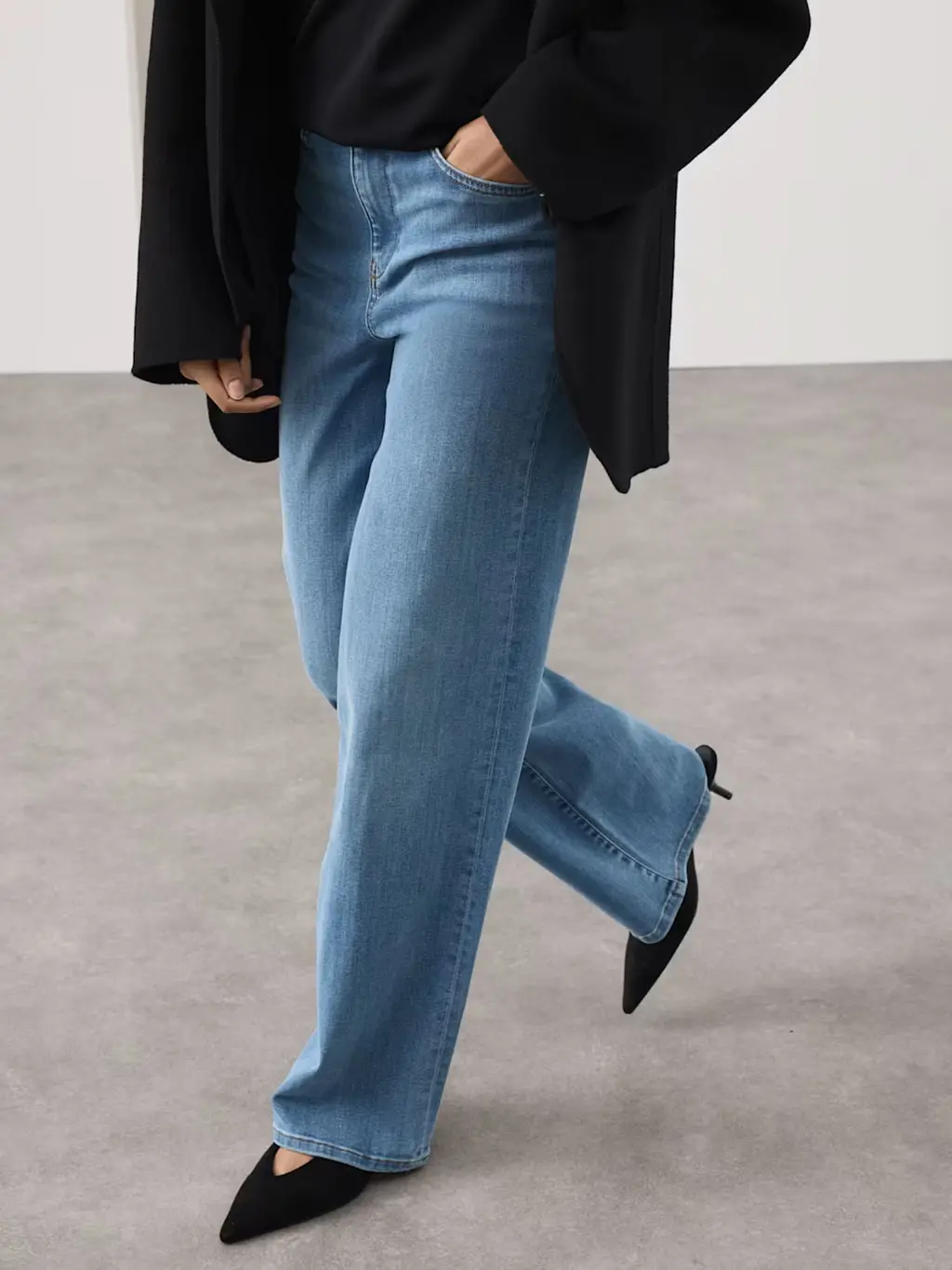Woman wearing blue wide-leg jeans with a black jumper, black blazer and pointed kitten heels