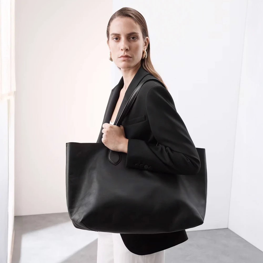 Woman wearing black linen blazer and oversized black leather tote bag