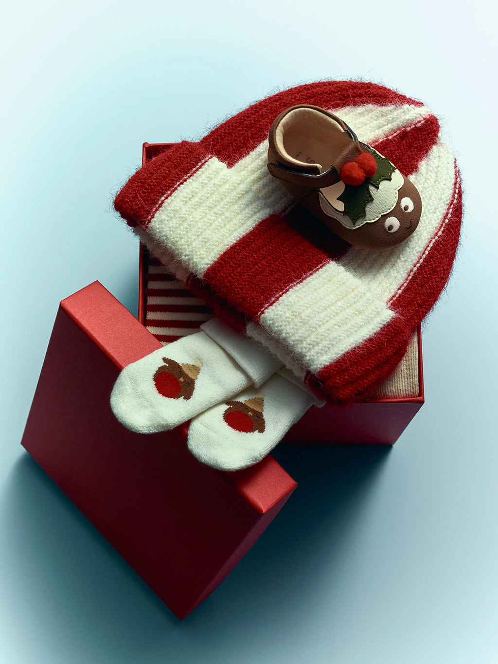 Group of kids' presents including a striped beanie hat, robin socks and mini holly shoes.