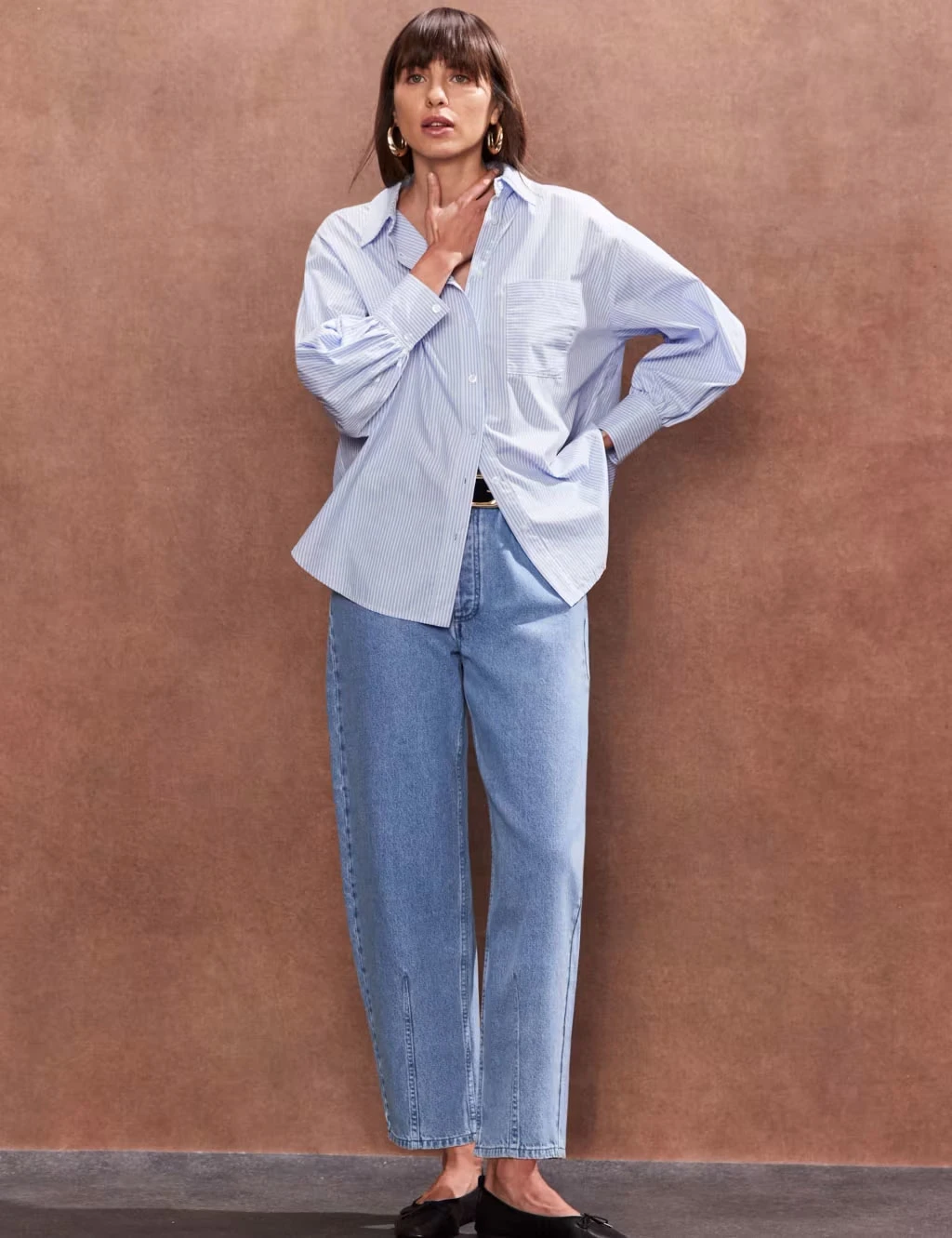 Woman wearing oversized cotton shirt and faded blue jeans