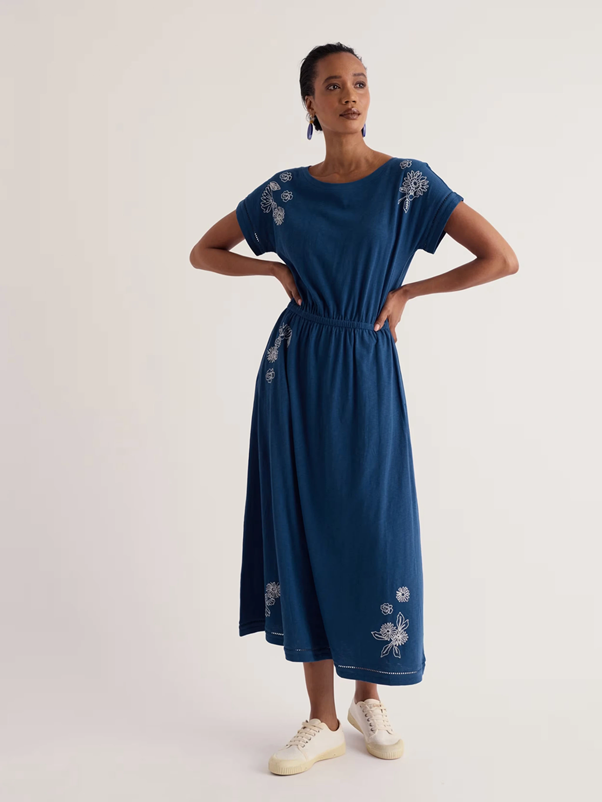 Woman wearing a blue cotton midi dress with white embroidery.