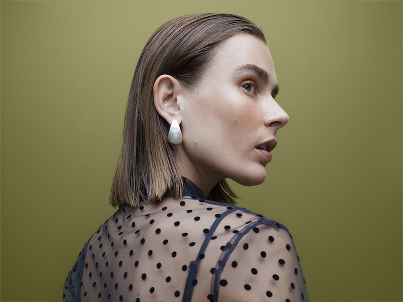 Woman wearing sheer black polka-dot blouse