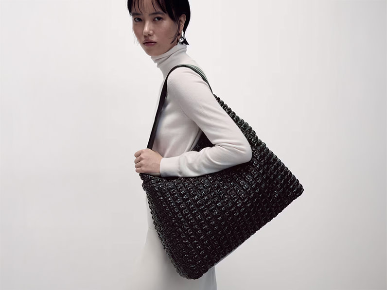 Woman wearing white polo-neck top and a black quilted shoulder bag