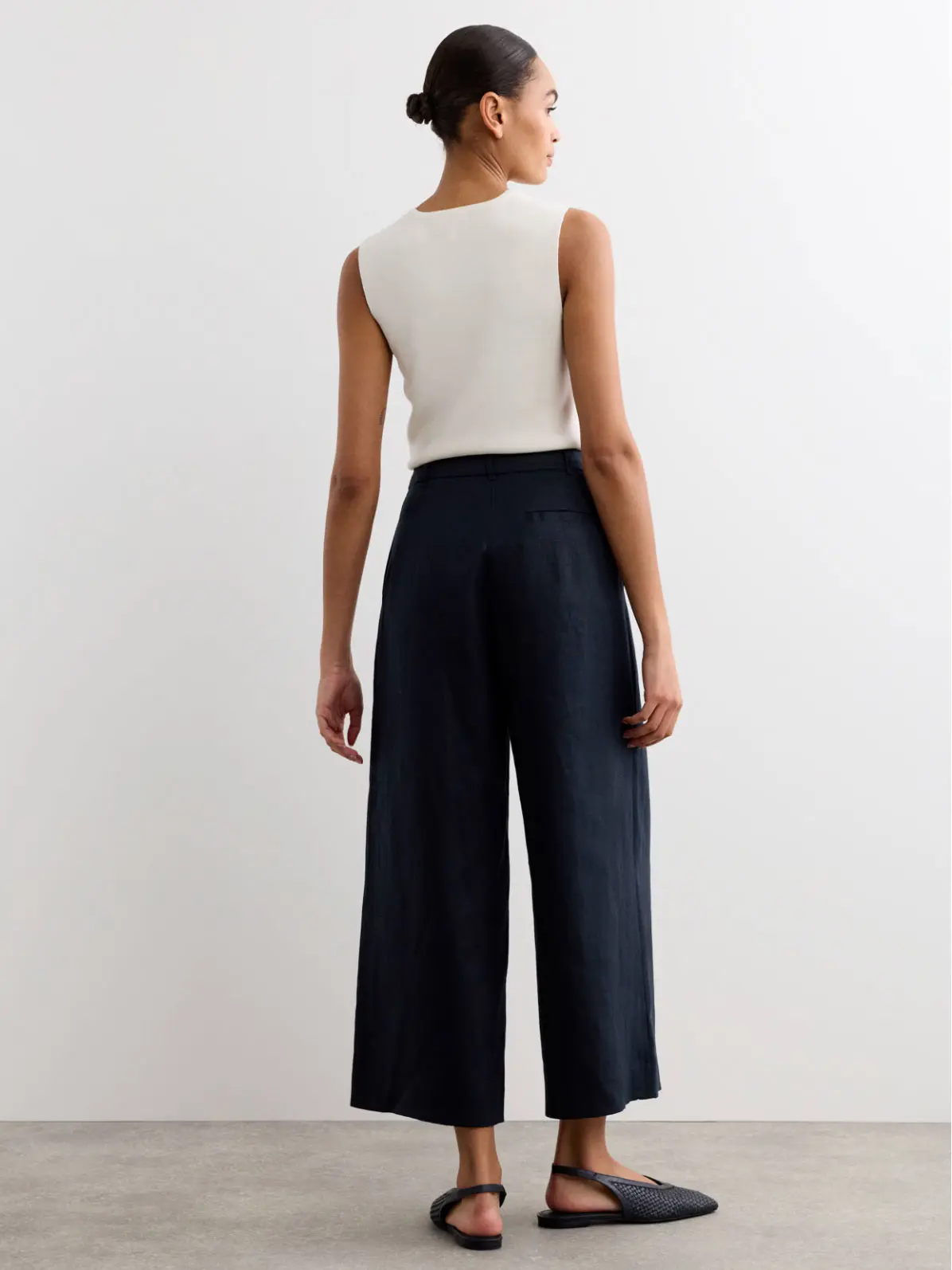 Woman wearing white top, a pair of culottes and pointed flats 