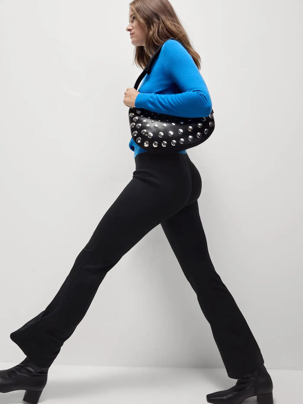 Woman wearing black flared trousers and a blue jumper