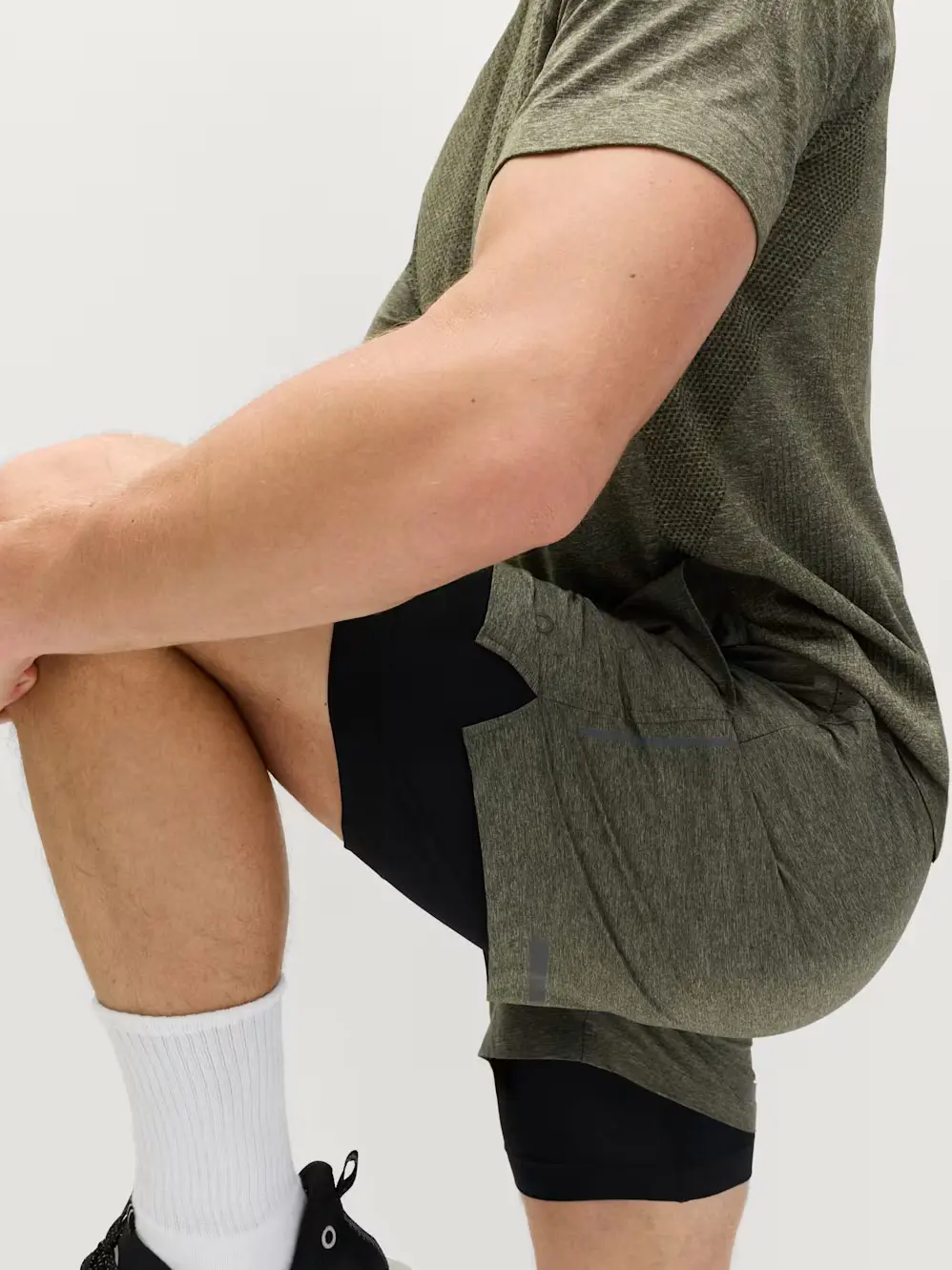 Man stretching wearing olive green shorts and T-shirt