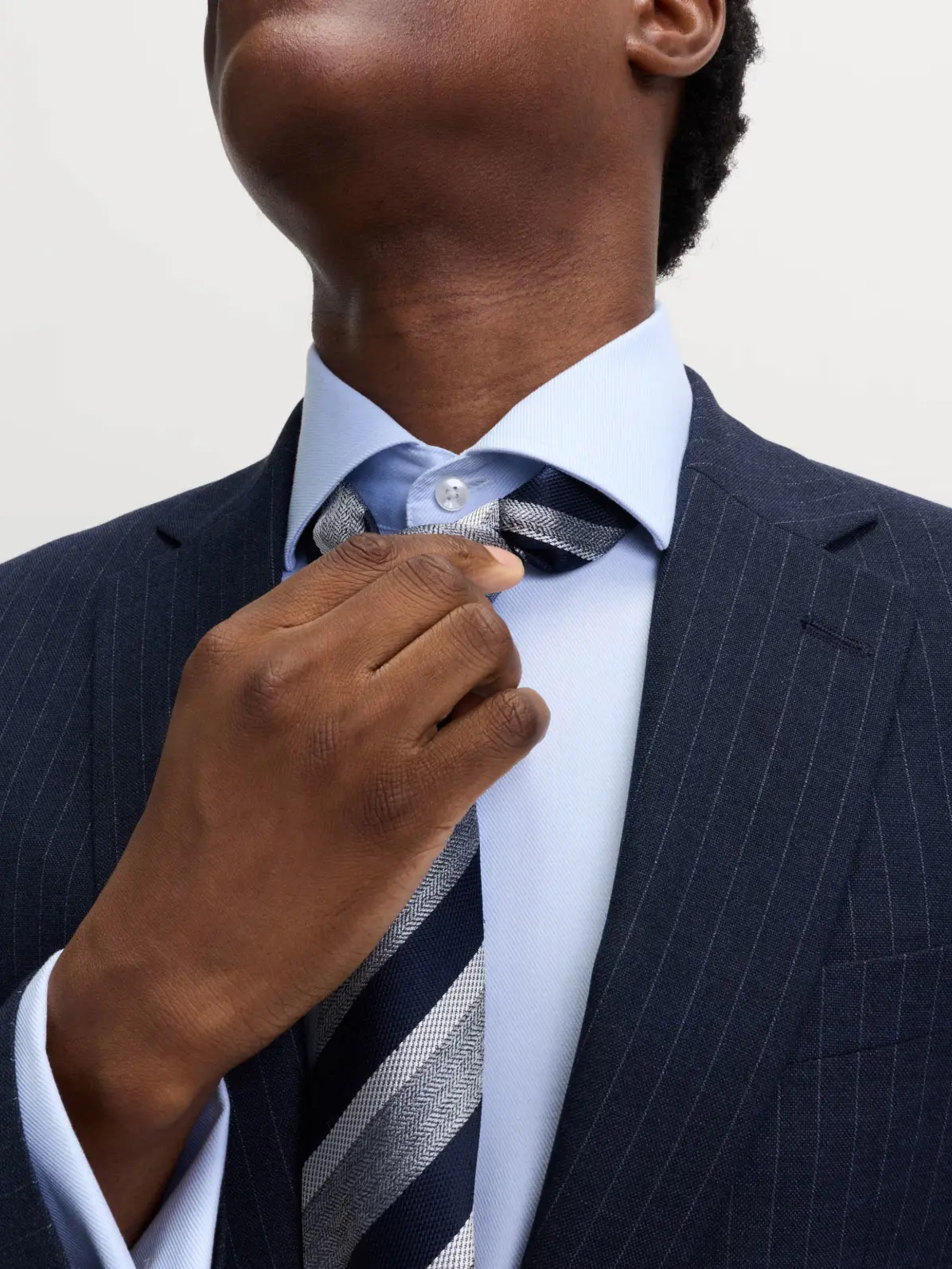 Man wearing navy striped blazer over blue shirt and striped tie 