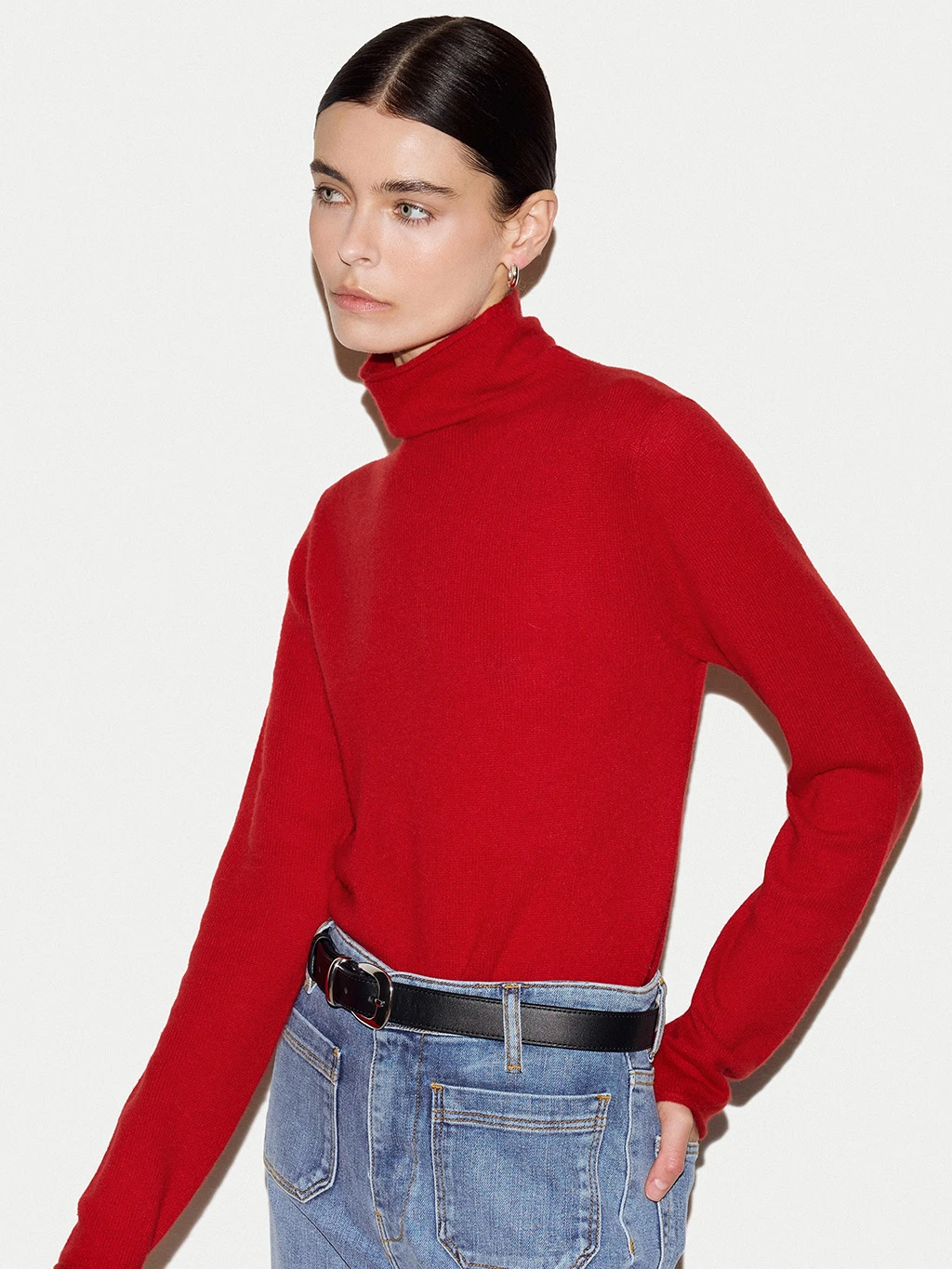 Woman wearing a bright red polo neck cashmere jumper.