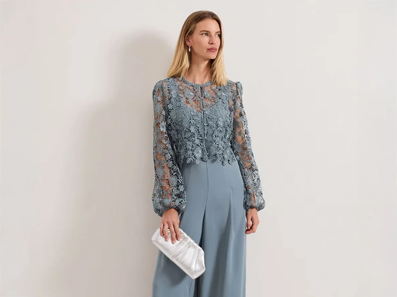 Woman wearing blue lace jumpsuit and silver clutch bag