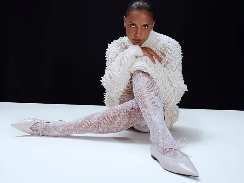 Woman wearing a white jumper with white lace tights and pointed pumps