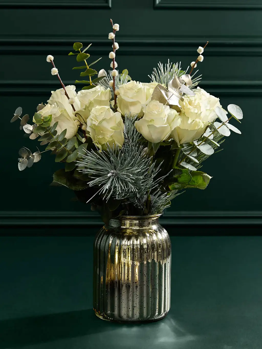 Seasonal bouquet with white roses, eucalyptus and metallic silver vase.