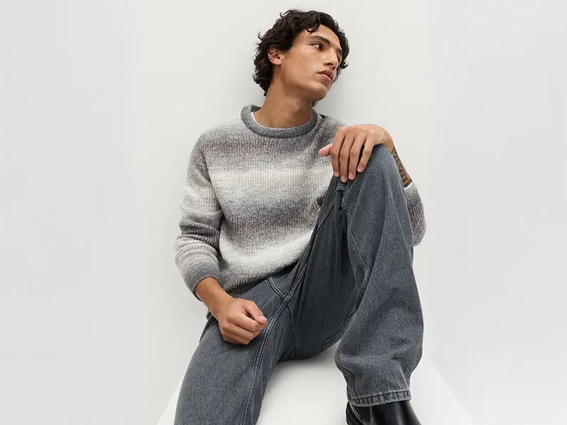 Man wearing grey striped jumper with jeans and black boots