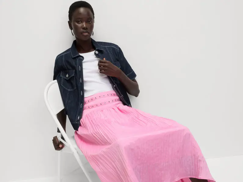 Woman wearing a pink skirt, white T-shirt and denim jacket