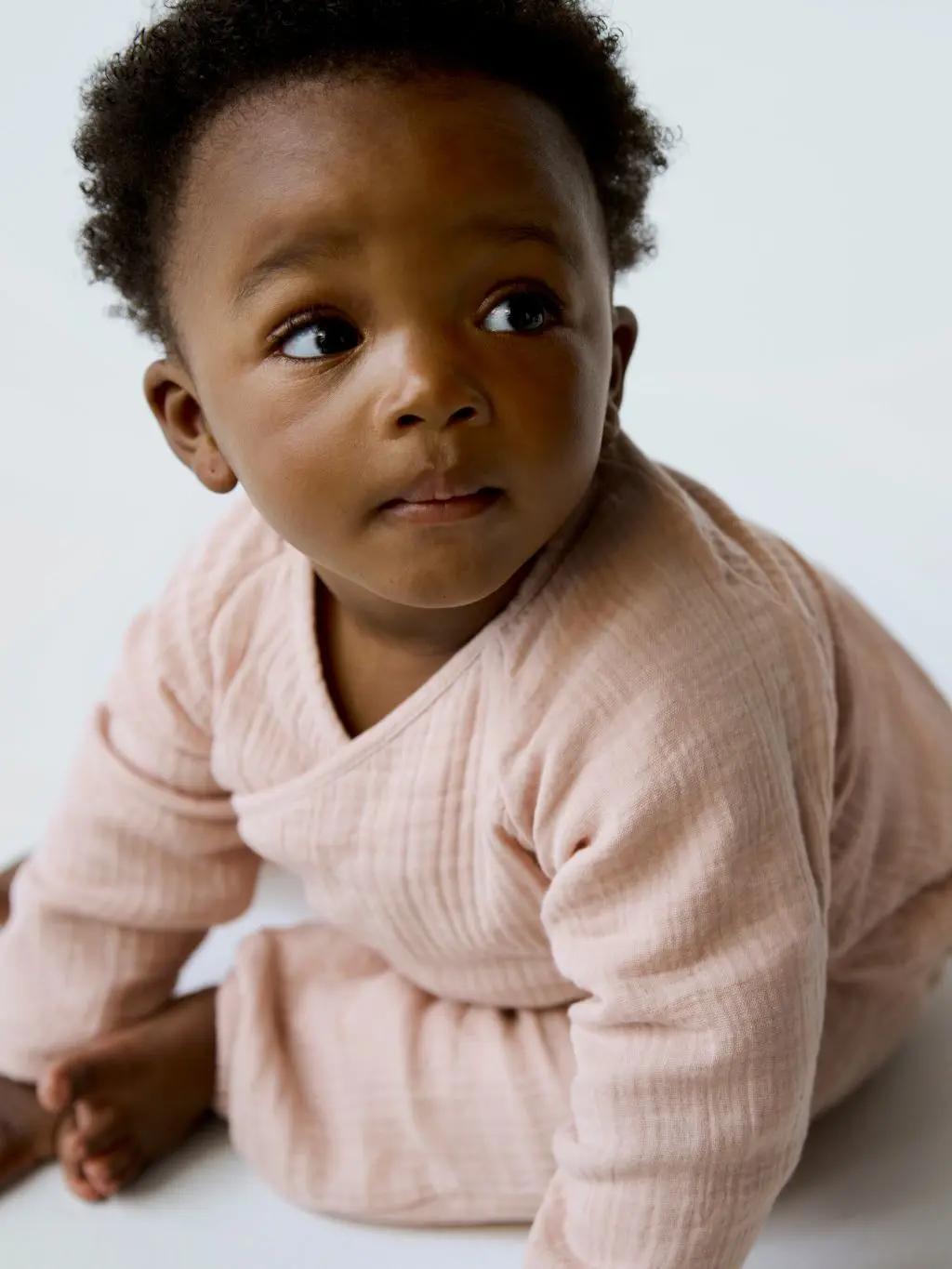 A baby wears a peach sleepsuit