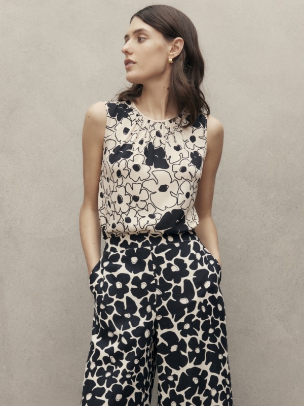 Woman wearing black and white patterned top and trousers. Shop Jaeger