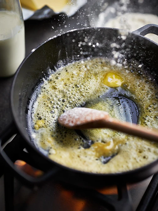 Butter cooking in cast iron pan with wooden spoon
