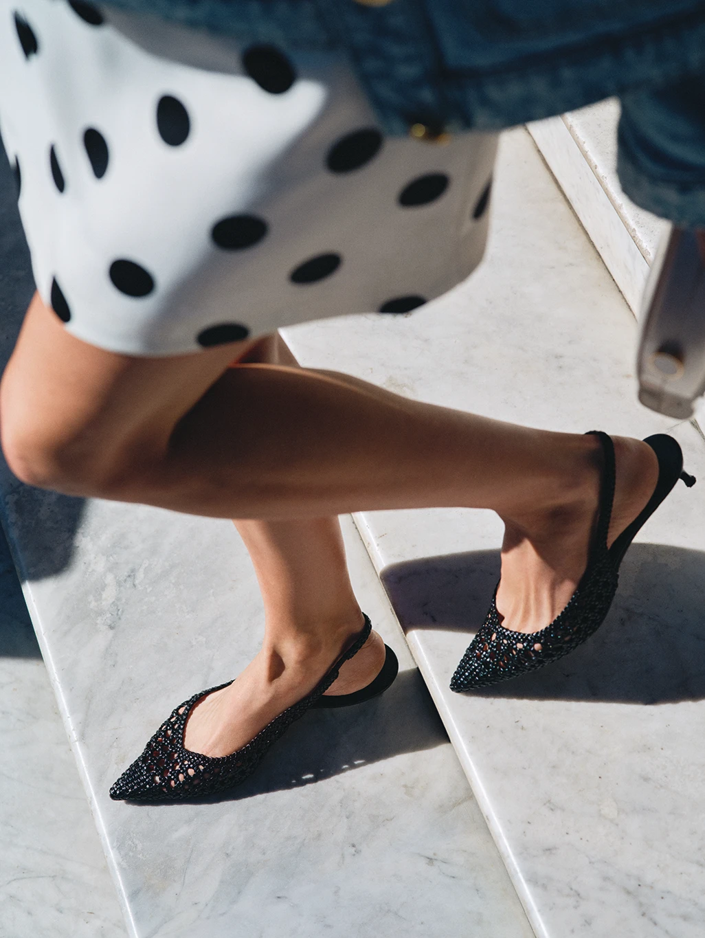 Woman wearing a black and white polka-dot mini skirt with black pointed heels