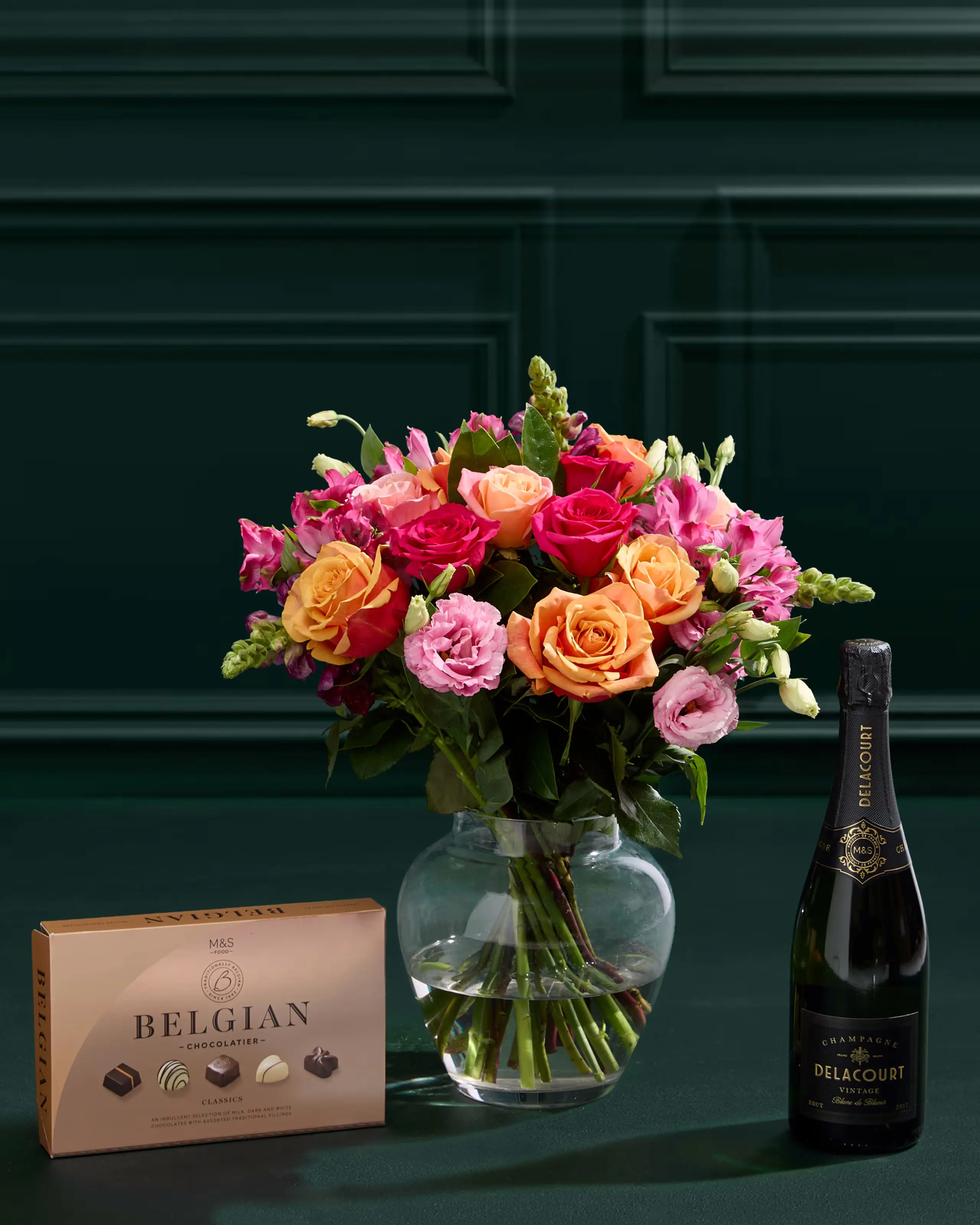 Bouquet of roses in a vase with chocolates and champagne