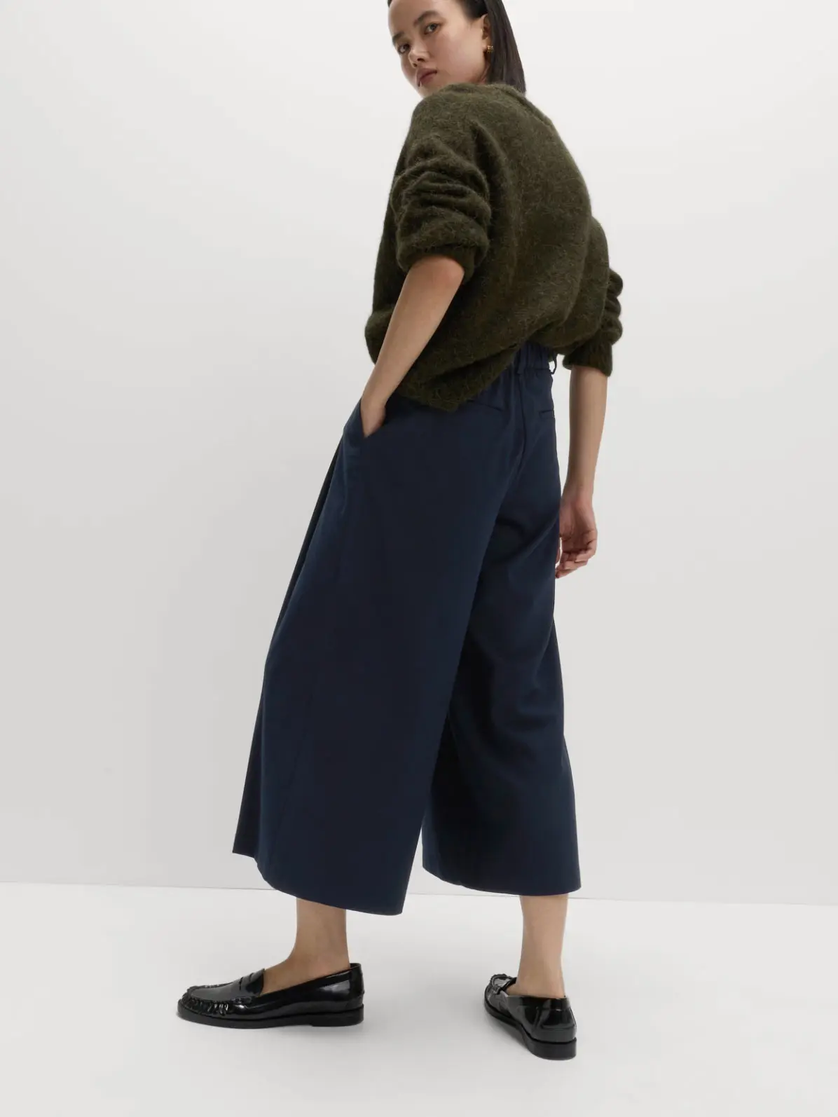 Woman wearing a green jumper, culottes and black loafers 