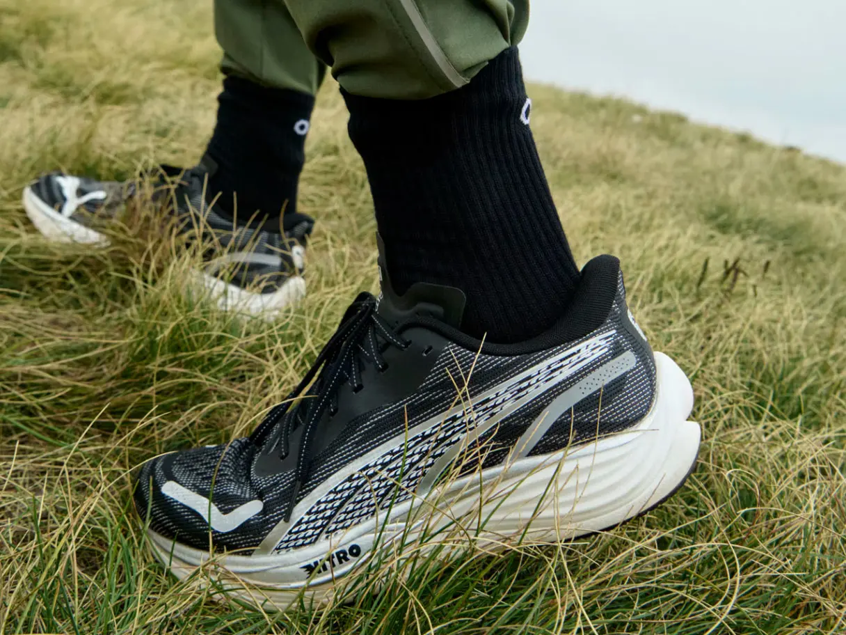 Person wearing black trainers and walking in a field