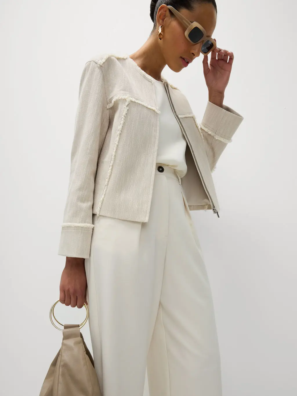 Woman wearing a raw-edge blazer, white trousers and chic accessories to the races