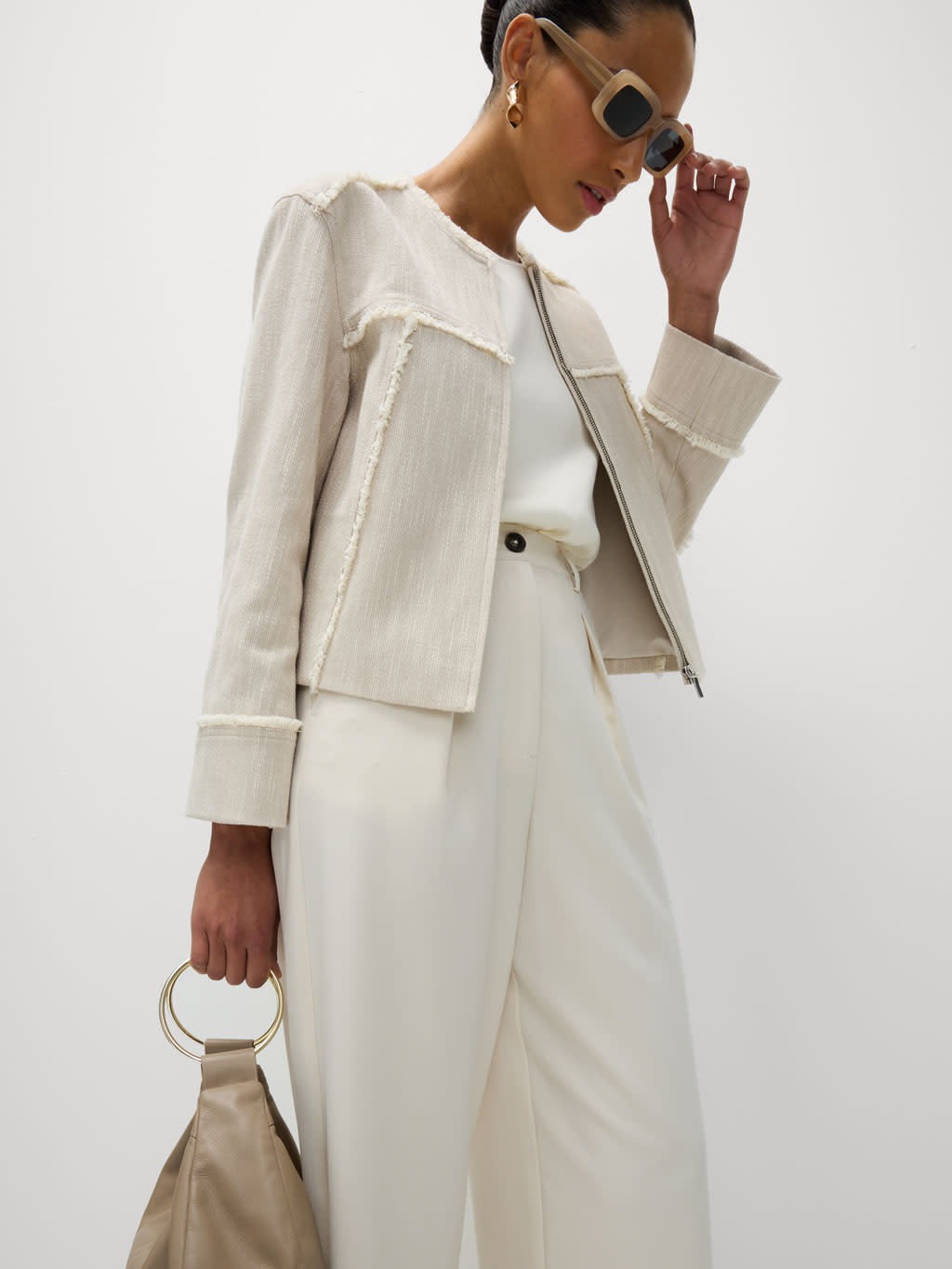 Woman wearing a raw-edge blazer, white trousers and chic accessories to the races