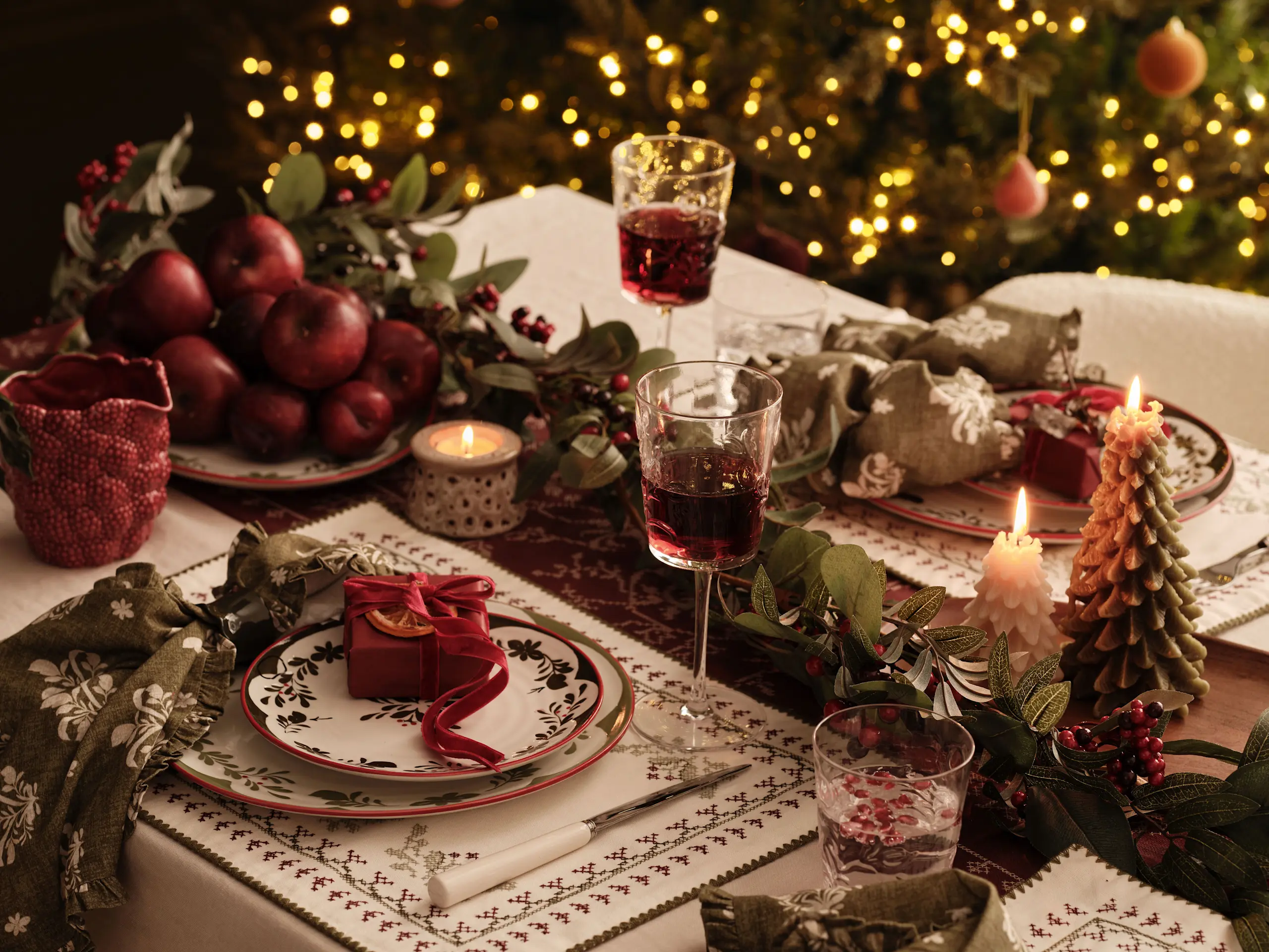 Image of festive table deco including plates, wine glasses, foliage and tree lights