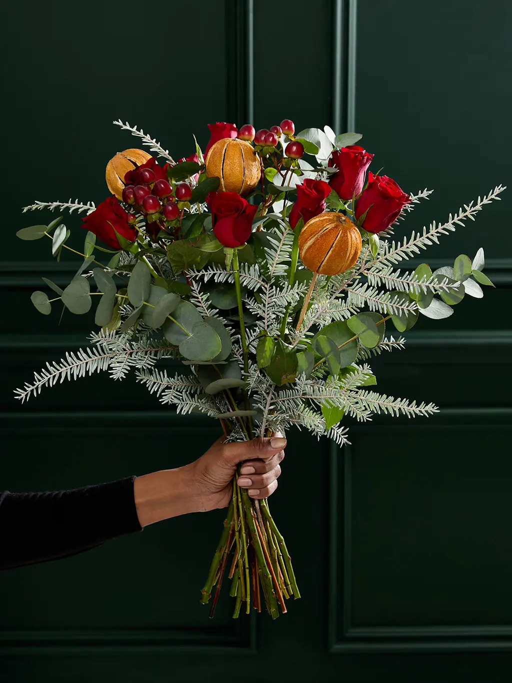 Bouquet of Christmas flowers with eucalyptus, red roses and dried oranges.