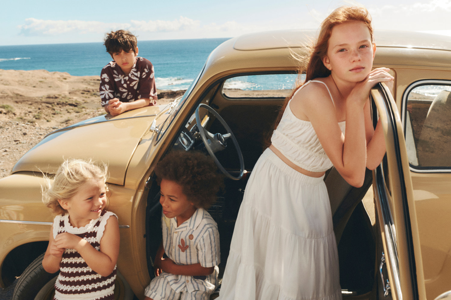 Children wearing holiday clothing outside a car