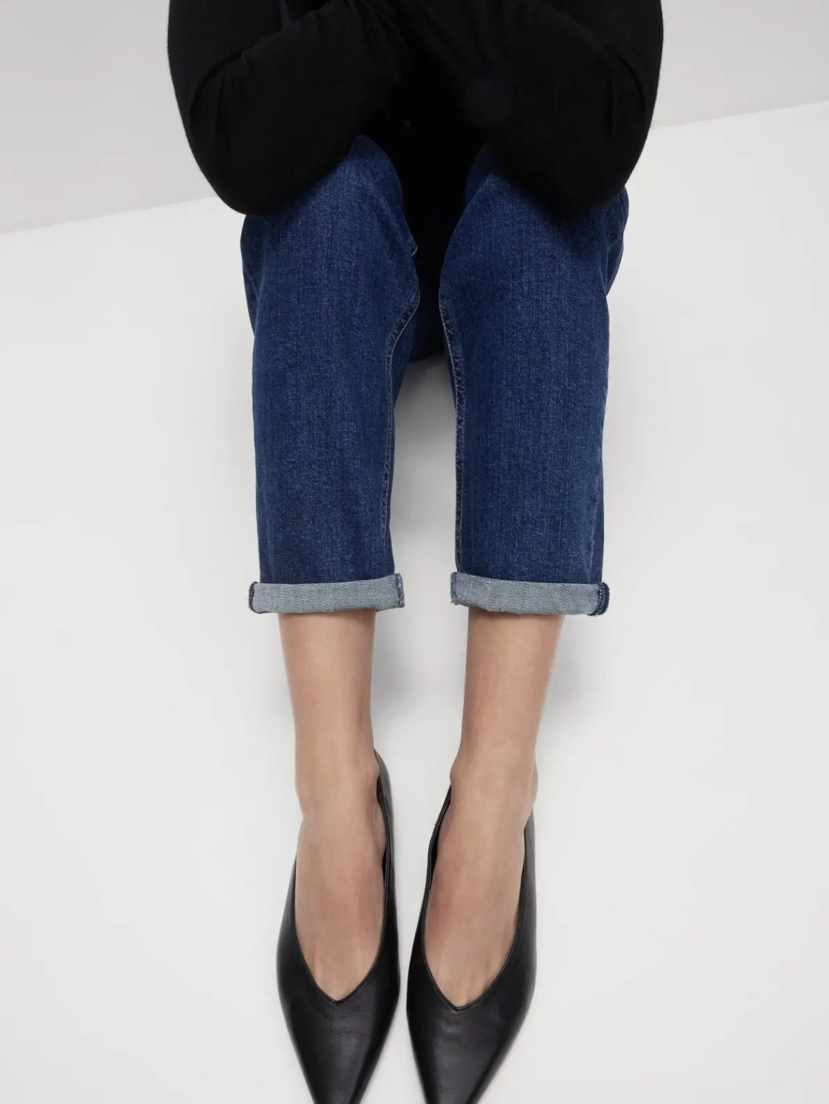 Woman wearing blue jeans and black pointed flats