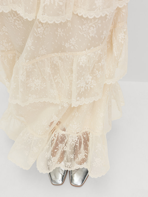 Woman wearing cream lace maxi skirt and silver shoes