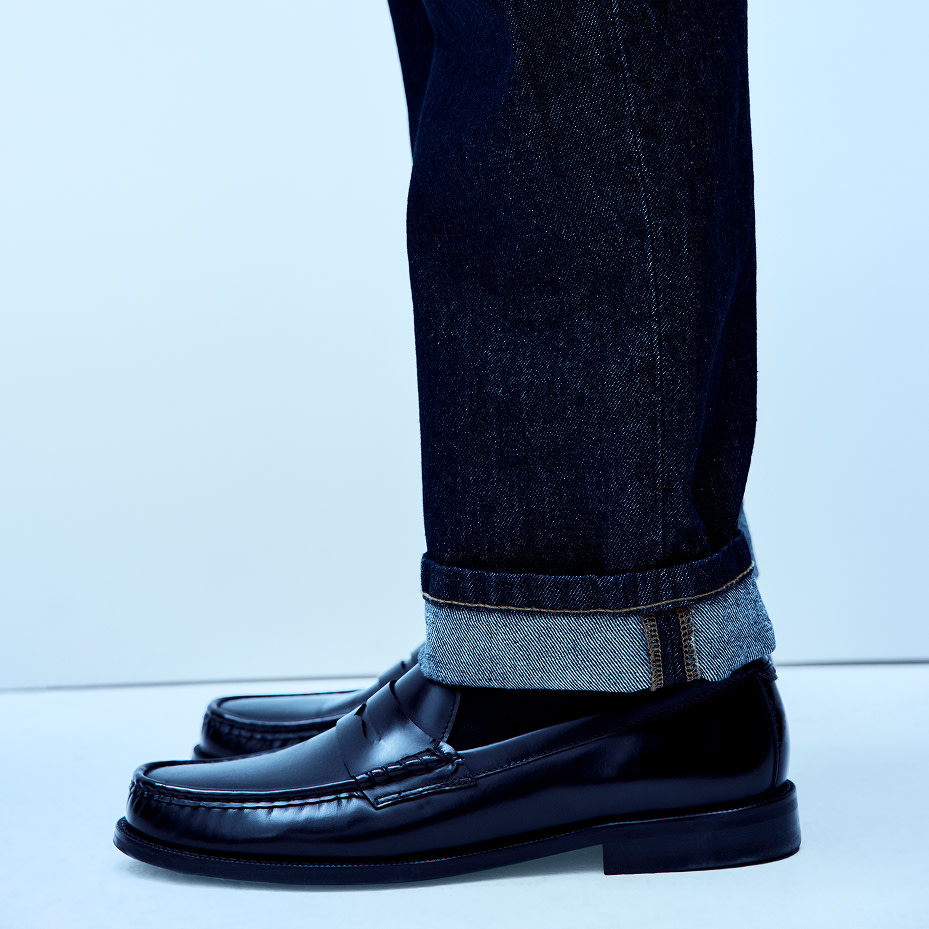 Man wearing black loafers and cuffed jeans
