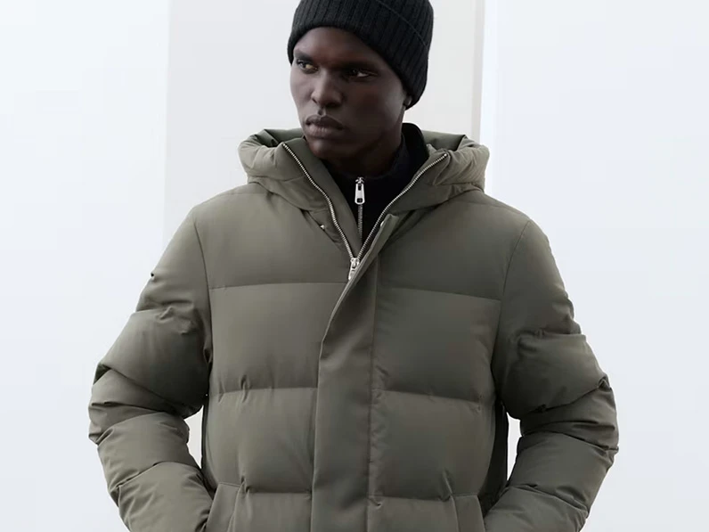 Man wearing an olive green puffer coat and a black beanie hat.