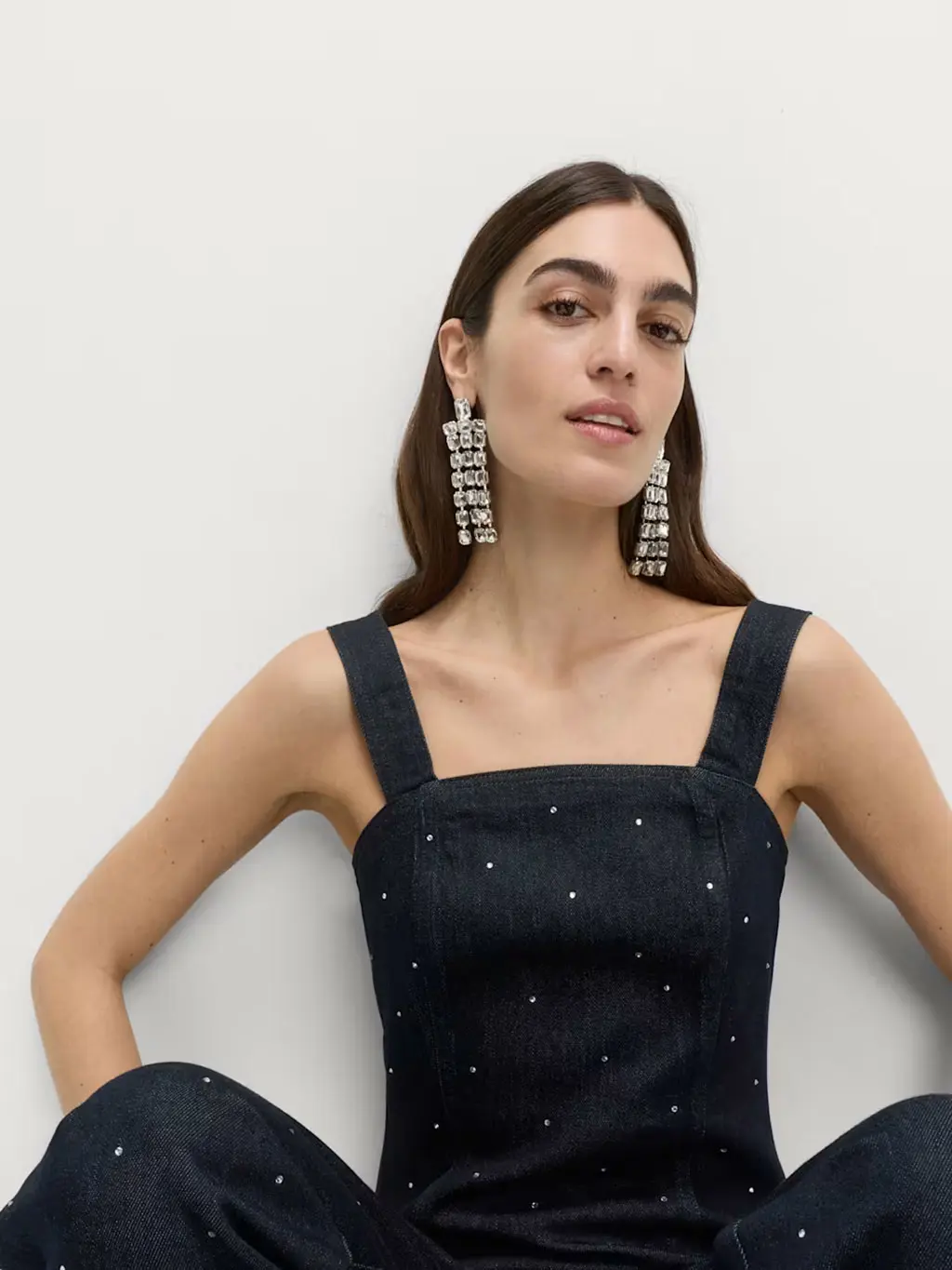 Woman wearing studded denim top with matching jeans and crystal drop earrings