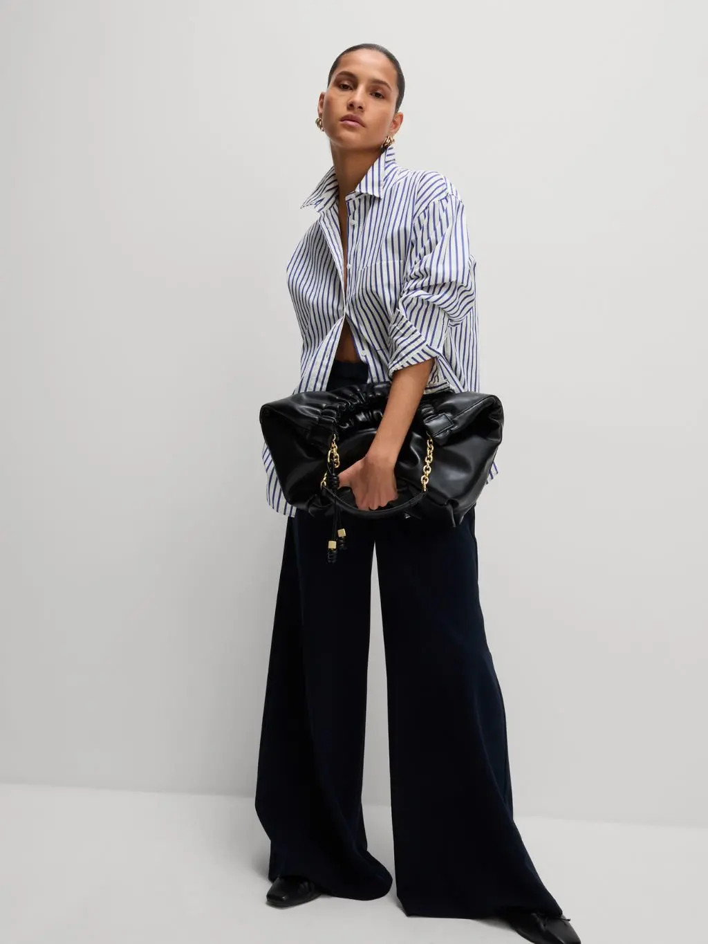 Woman wearing blue striped oversized shirt with black wide-leg trousers
