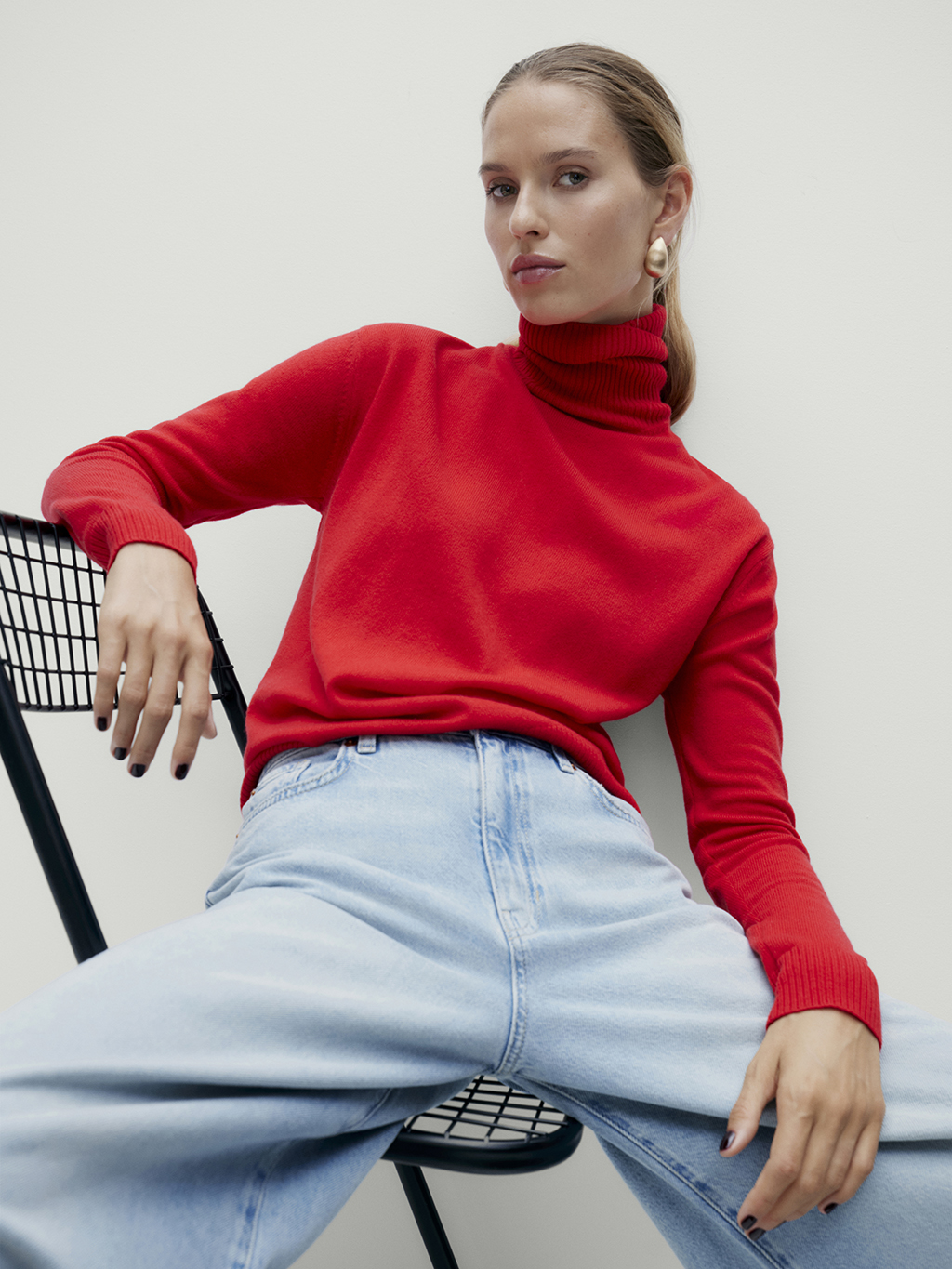 Woman wearing red poloneck jumper and light blue jeans