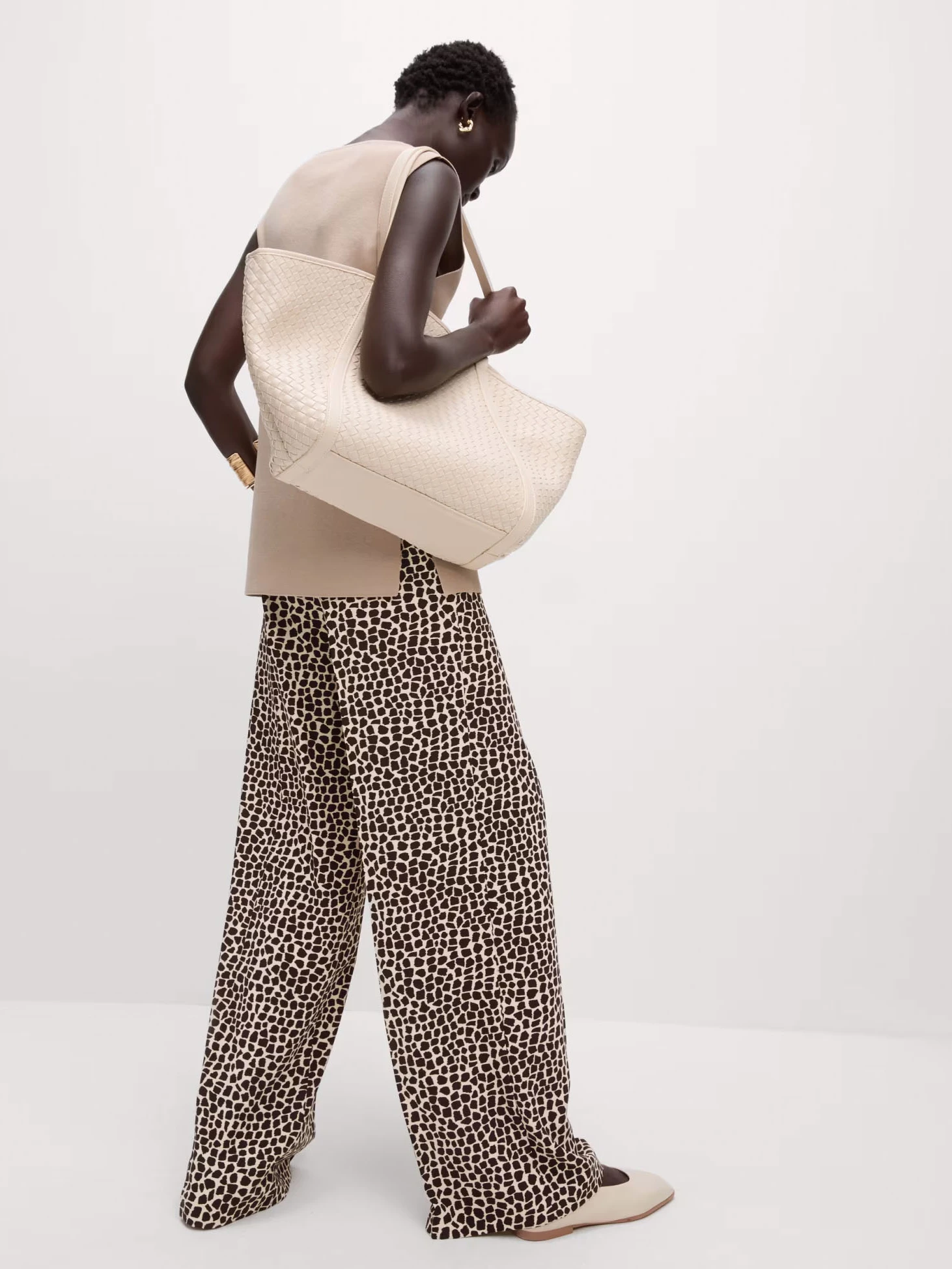 Woman wearing animal-print trousers and carrying an oversized tote bag