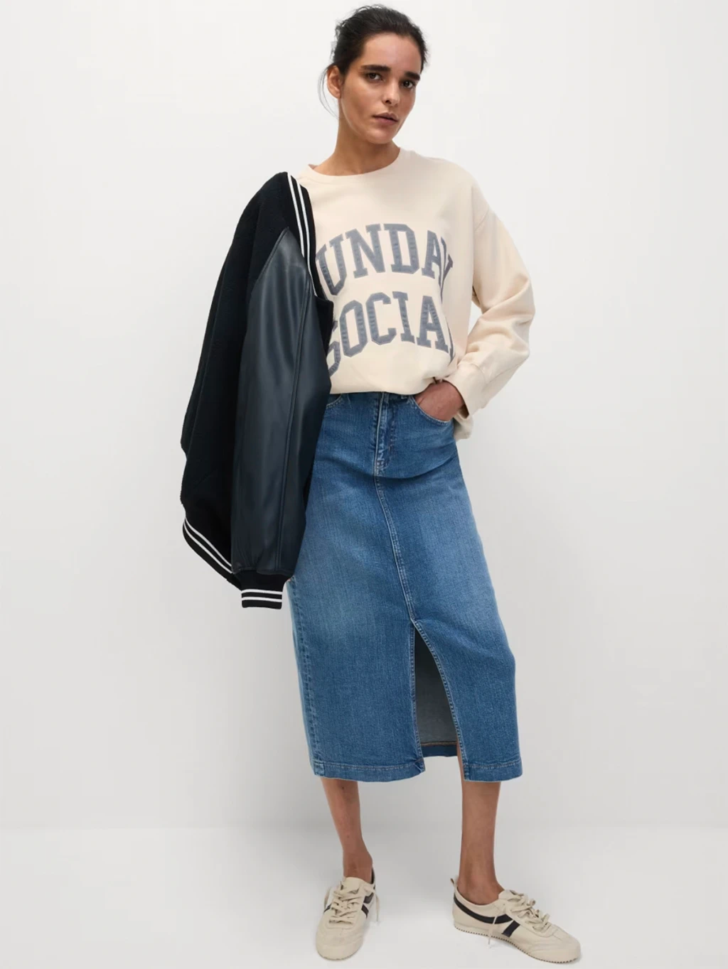 woman wearing cream sweatshirt, denim skirt and trainers