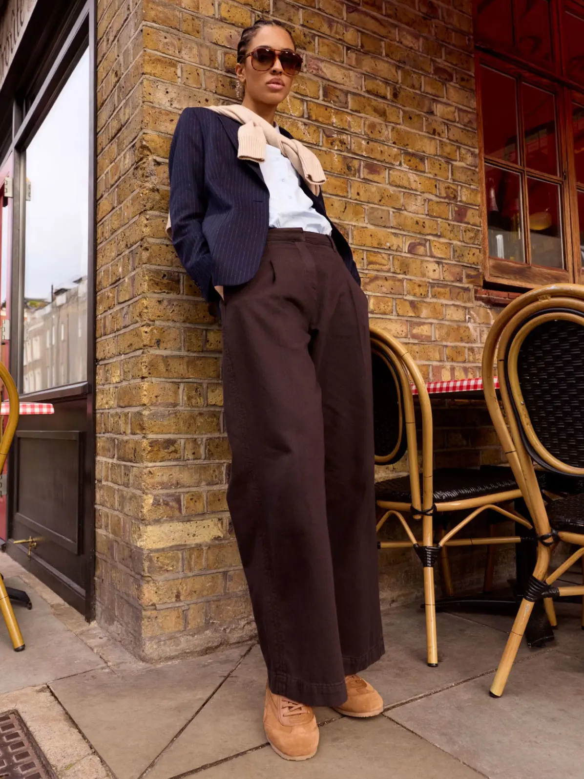 Woman wearing brown trousers with white T-shirt, navy blazer and brown trainers