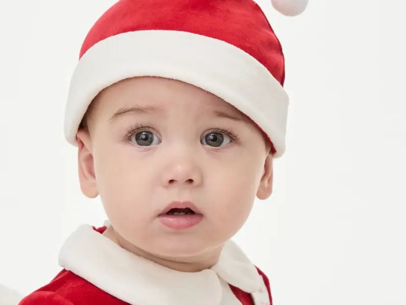 A baby wearing a Santa hat and outfit