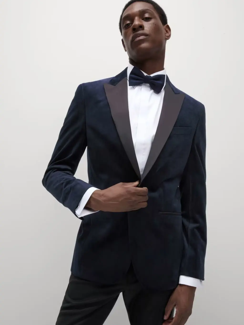 A man wearing a black tuxedo jacket, white shirt and black bow tie