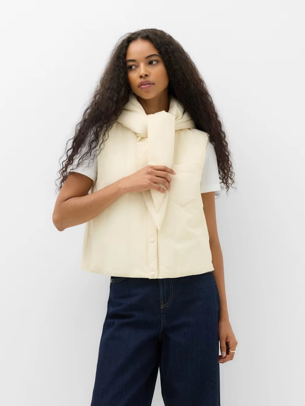 Woman wearing a cream hoodie gilet with a tie neck detail.