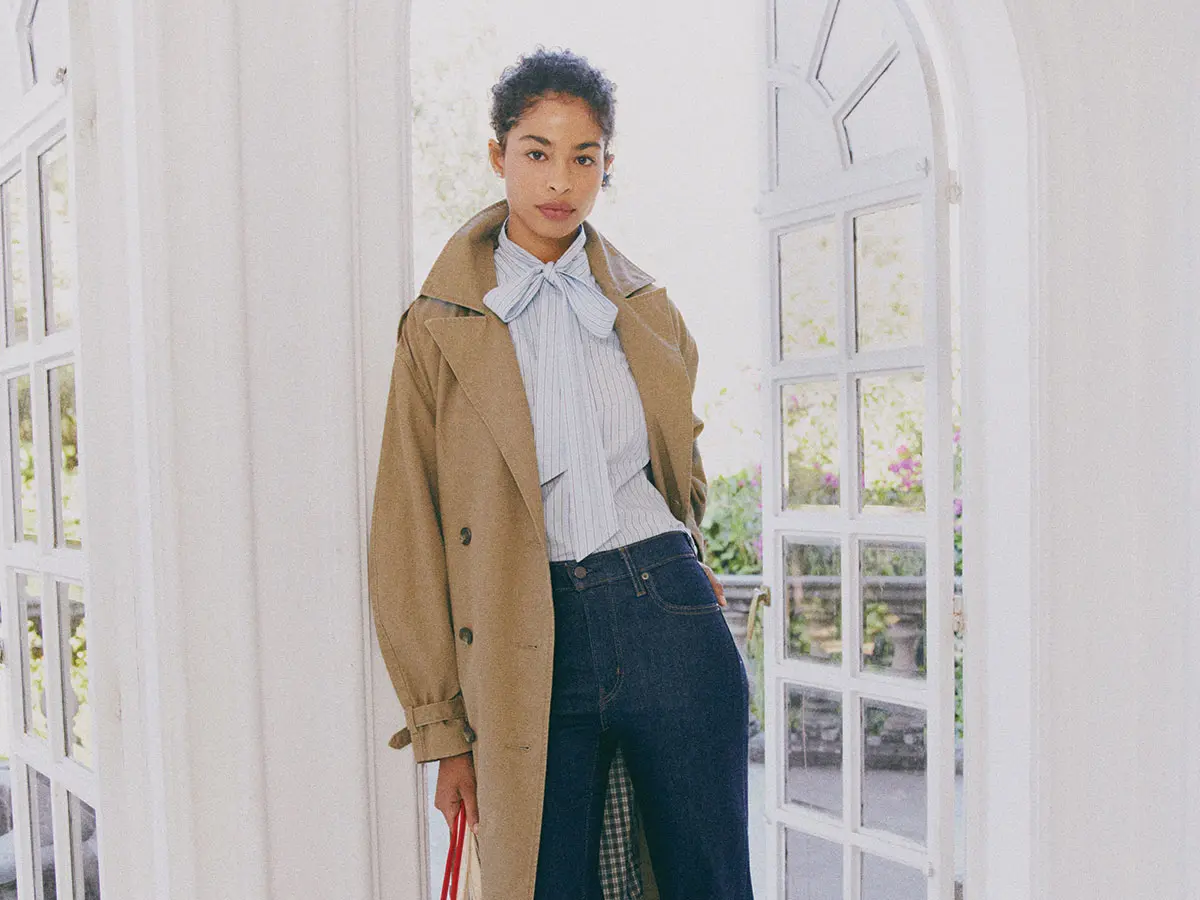 Woman wearing trench coat, shirt and dark indigo Levi's jeans