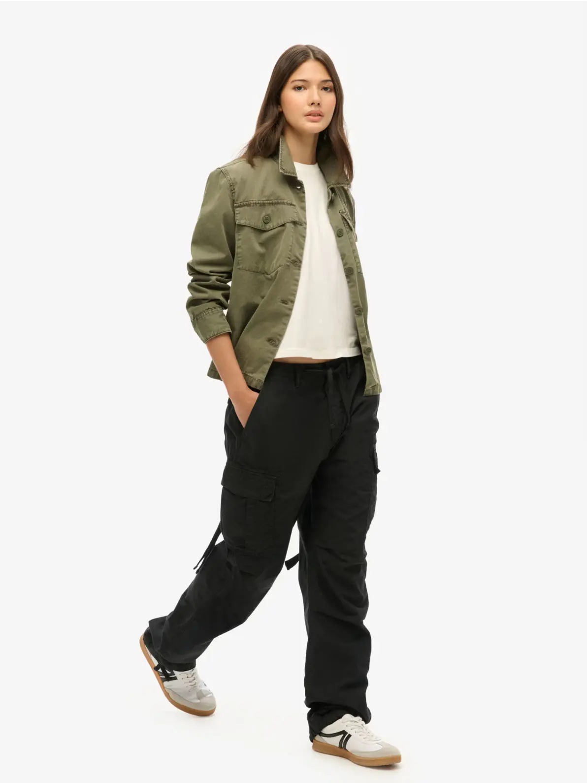 Woman wearing khaki jacket, white top, black cargo trousers and white trainers