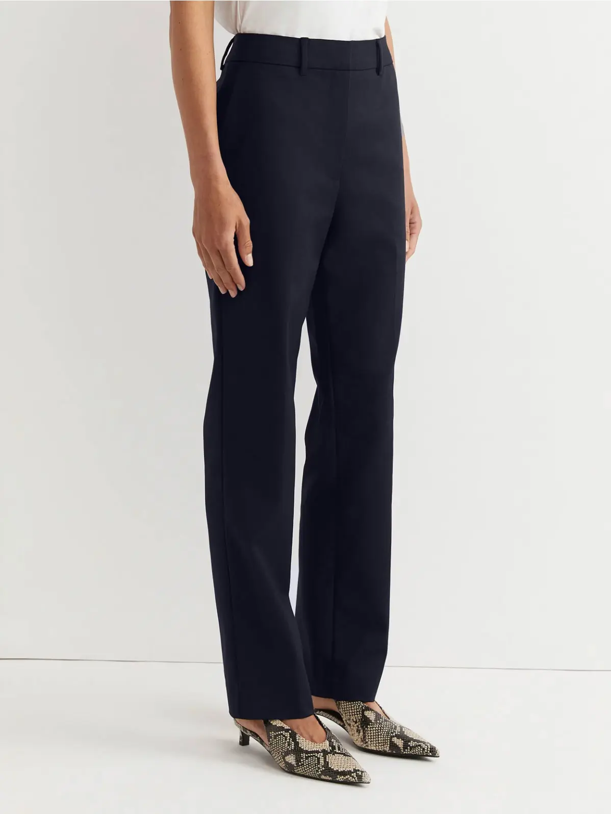 Woman wearing navy straight-leg trousers and animal-print kitten heels