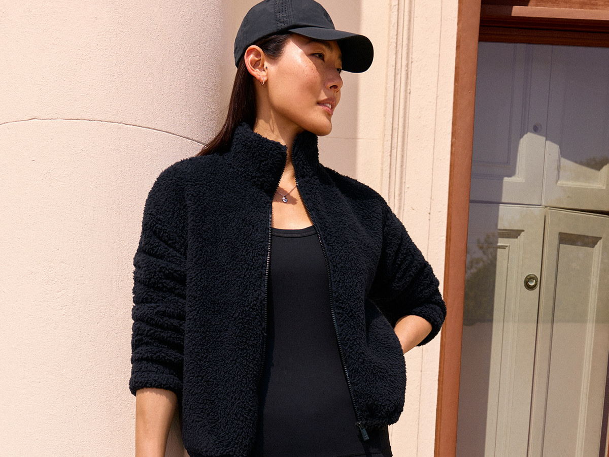 Woman wearing black cap, fleece and top by Sweaty Betty