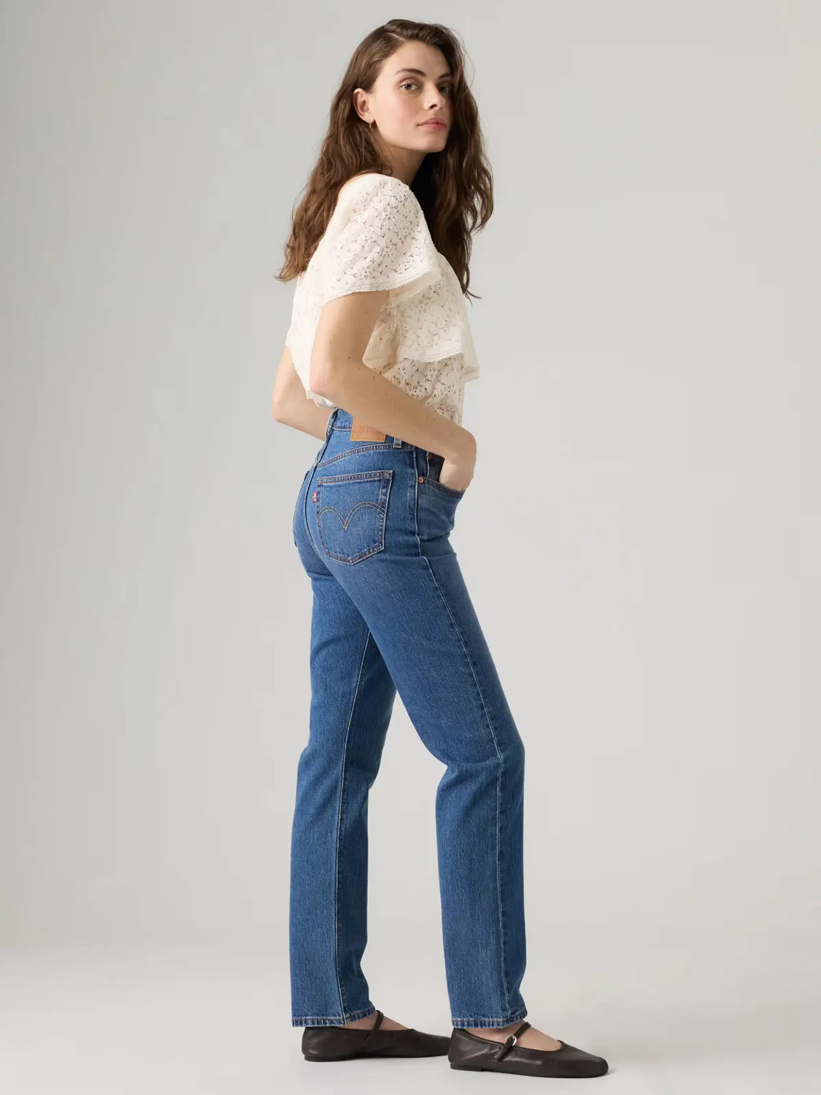 Woman wearing white top with blue jeans and flats 