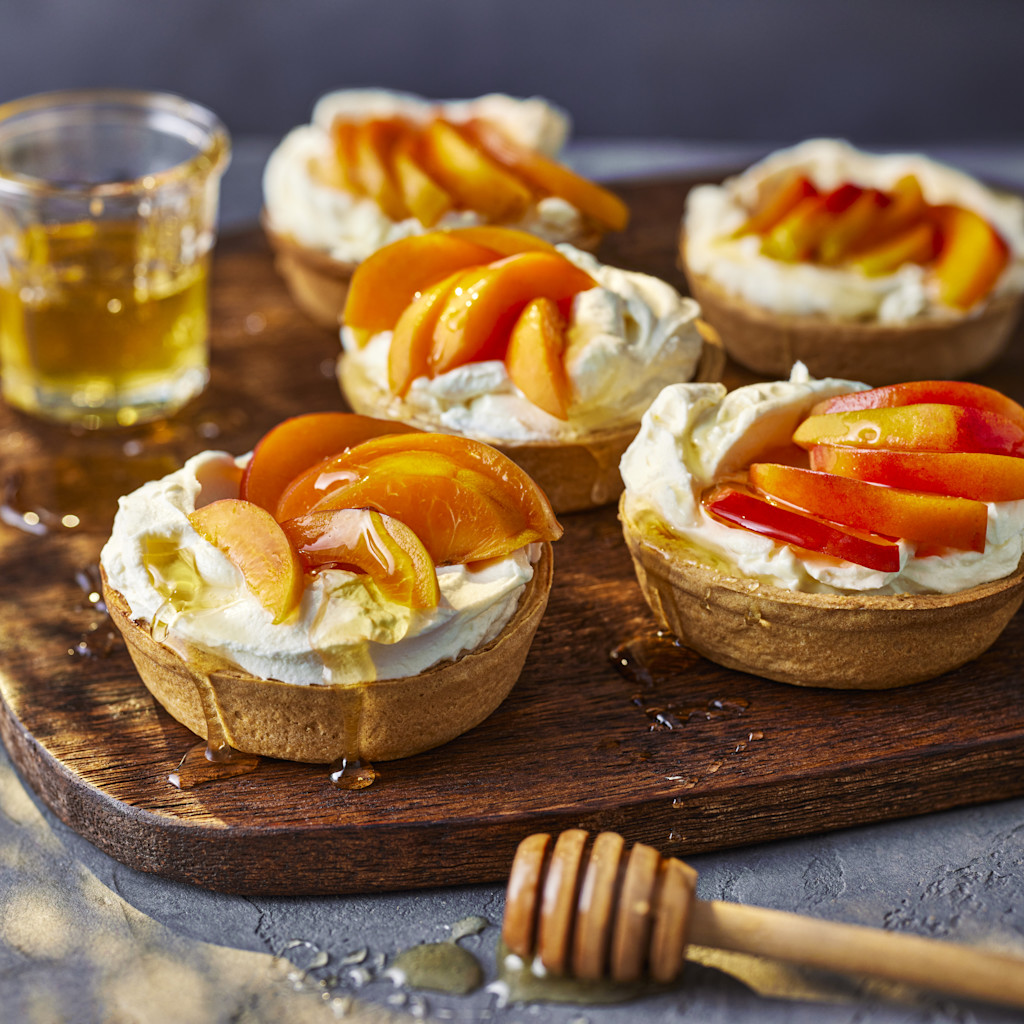 Peach, apricot and mascarpone tarts on wooden board